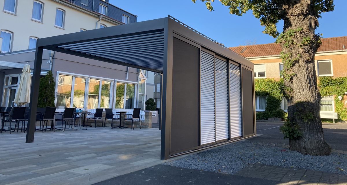 Unsere schiebaren Seitenwände mit Lamellen oder Spannrahmen, an einer Überdachung in Anthrazit und Weiß, bei Frimey GmbH.